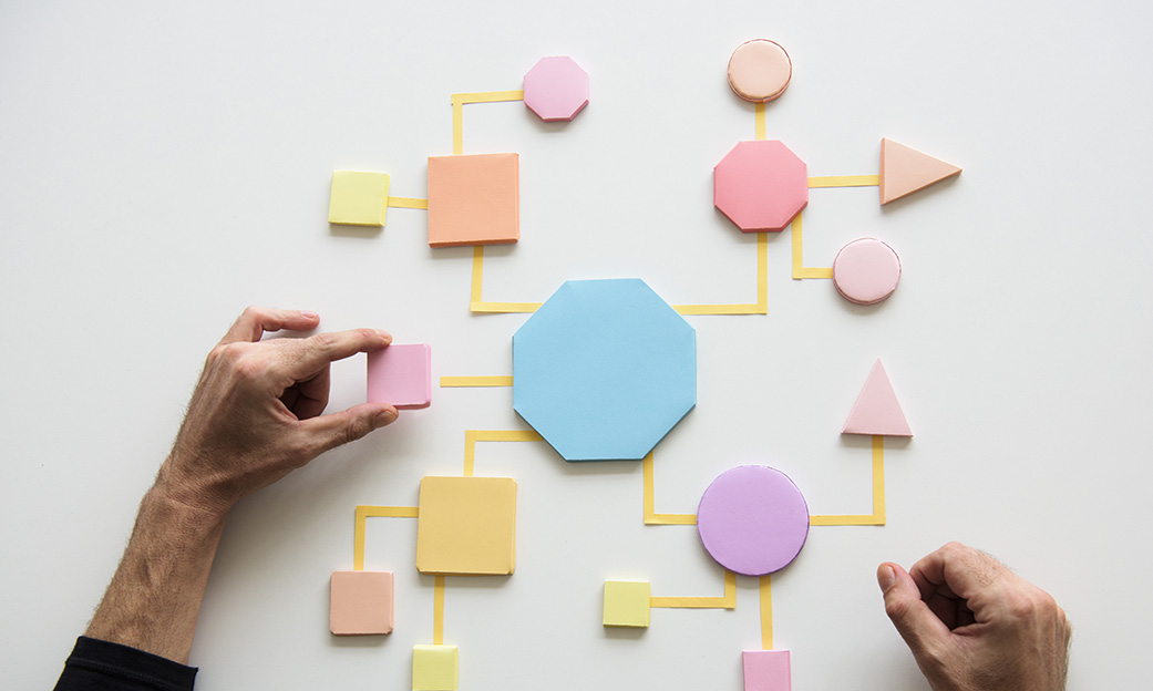 hands mapping a business process with workflow shapes